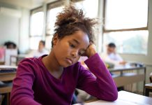 Menina olha triste para a mesa da escola; Repetência escolar: como buscar novos sentidos para o próximo ano letivo?