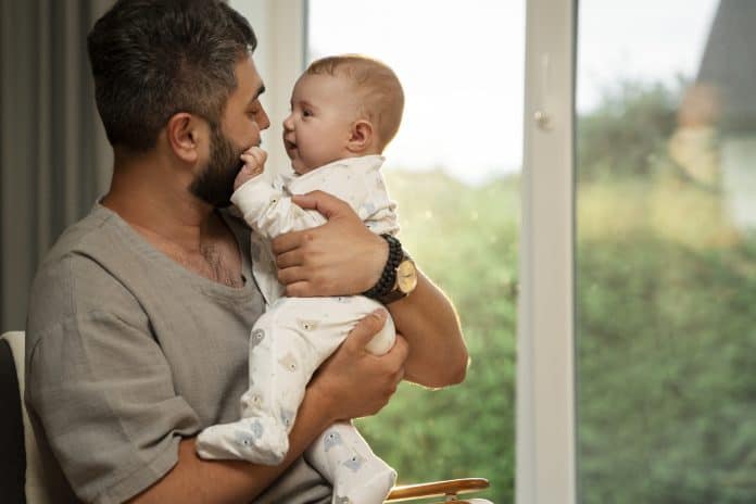 Pai segurando bebê; Quais são as mudanças na licença-paternidade no Brasil?