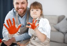 Pai atípico e filha com Síndrome de Down têm as mãos pintadas de laranja
