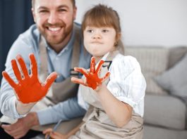 Pai atípico e filha com Síndrome de Down têm as mãos pintadas de laranja