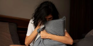 Adolescente com ansiedade abraça travesseiro na cama