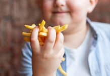 Menino obeso segura batatas fritas na mão