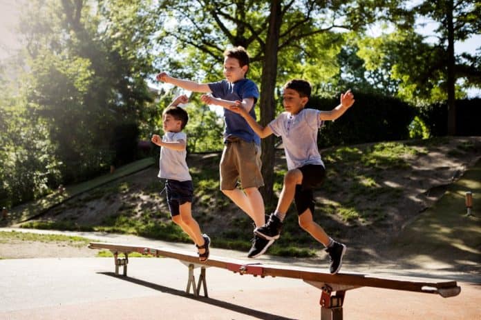 Meninos correm sob banco de madeira em parque