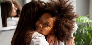 Mãe abraça filha de cabelos crespos; escuta ativa faz parte da proposta da CNV