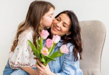 Mãe segura tulipas e recebe beijo da filha