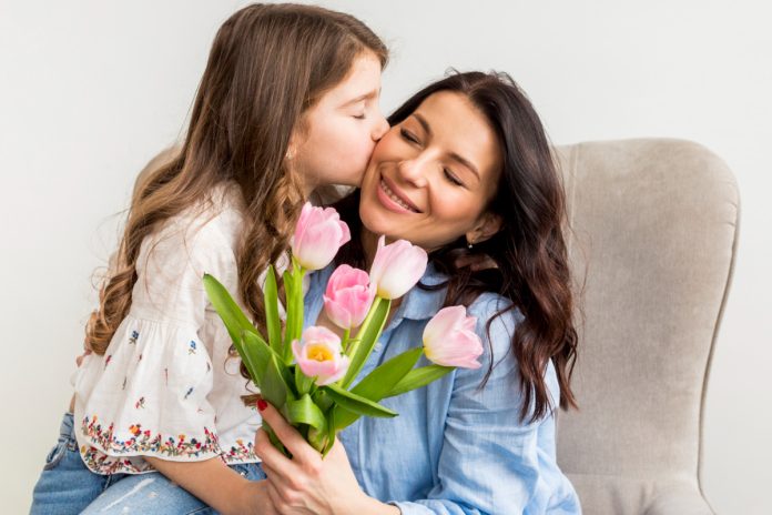 Mãe segura tulipas e recebe beijo da filha