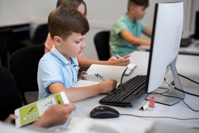 Crianças usam computador durante a aula