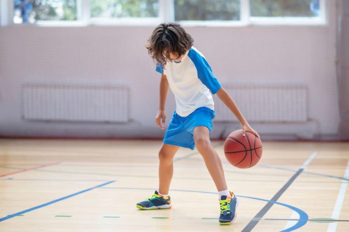 Menino joga basquete na quadra