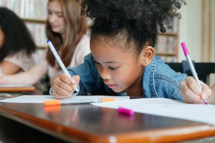 Aluna escreve em caderno em sala de aula