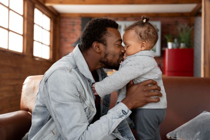 Pai negro encosta testa com testa de bebê