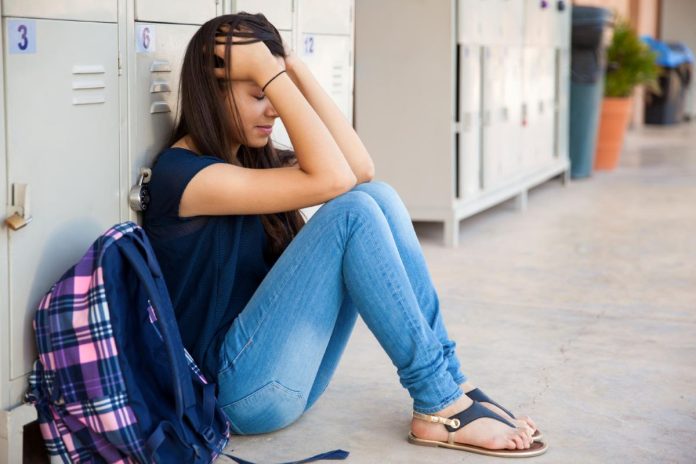 Adolescente está sentada no chão encostada em armário