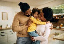 Mãe afro segura filho no colo que é abraçado pelo pai