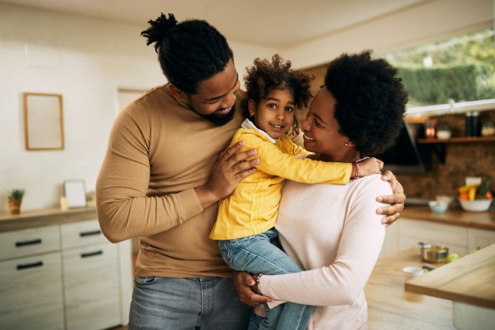 Mãe afro segura filho no colo que é abraçado pelo pai