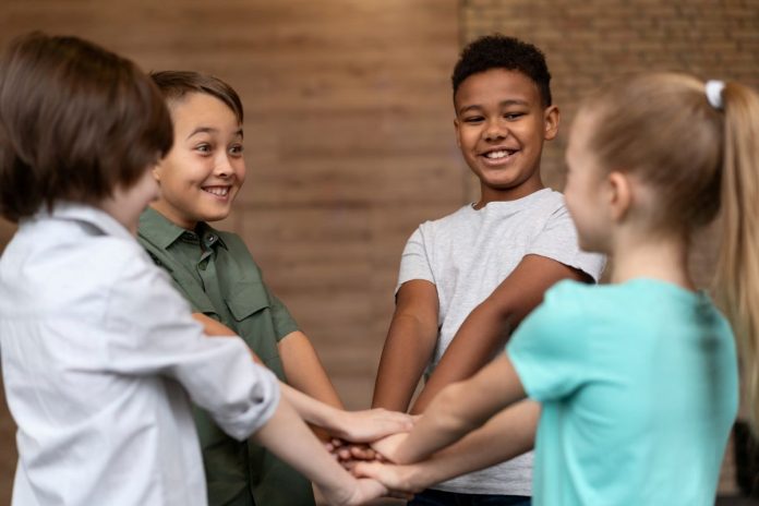 Alunos em círculo põem a mão umas sobre as outras