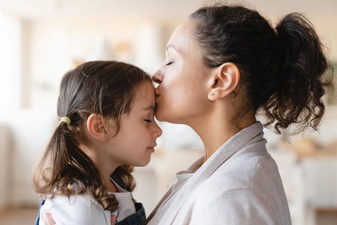 Mãe beija testa da filha