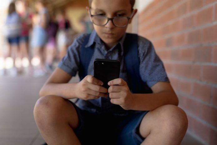 Menino usa celular na escola