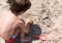 Menino brinca na areia da praia