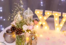 Flores e o número 15 em algarismo romanos decoram cenário de festa de 15 anos