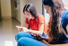 Duas adolescentes acessam redes sociais no celular