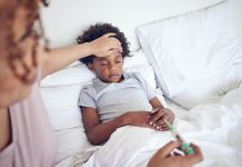 Menino afro com problemas respiratórios está deitado na cama