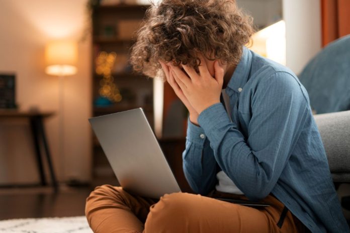 Menino esconde rosto com laptop no colo