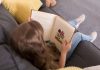 Menina lê livro no sofá