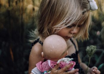Menina segurando uma boneca
Foto: Freepik