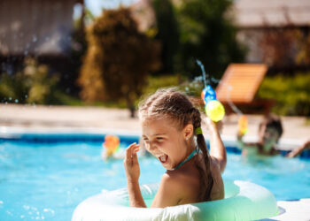 Criança na piscina, brincando no sol
Foto: Freepik